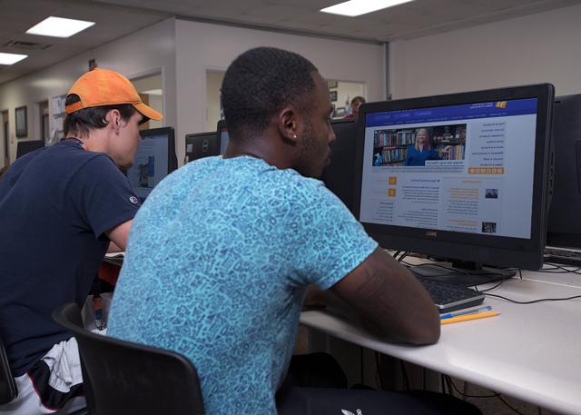 学生 sitting at a computer in a computer lab.